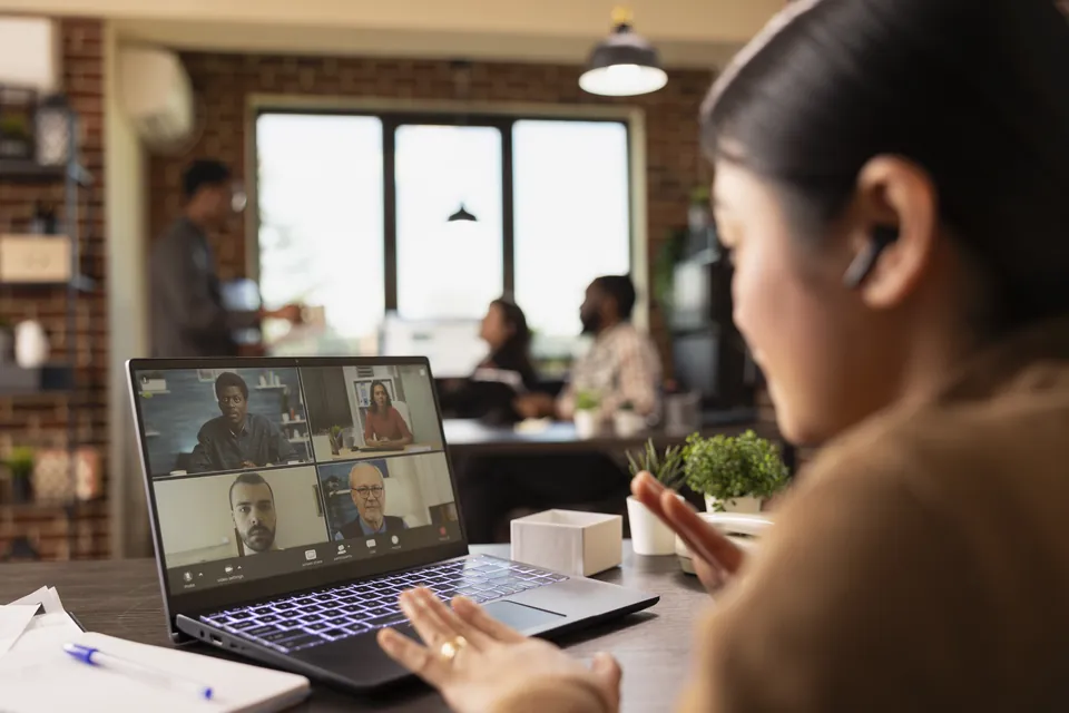 A woman joining a video meeting from a laptop in a café