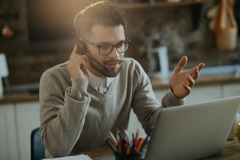 A person wearing a headset during a conversation at their laptop