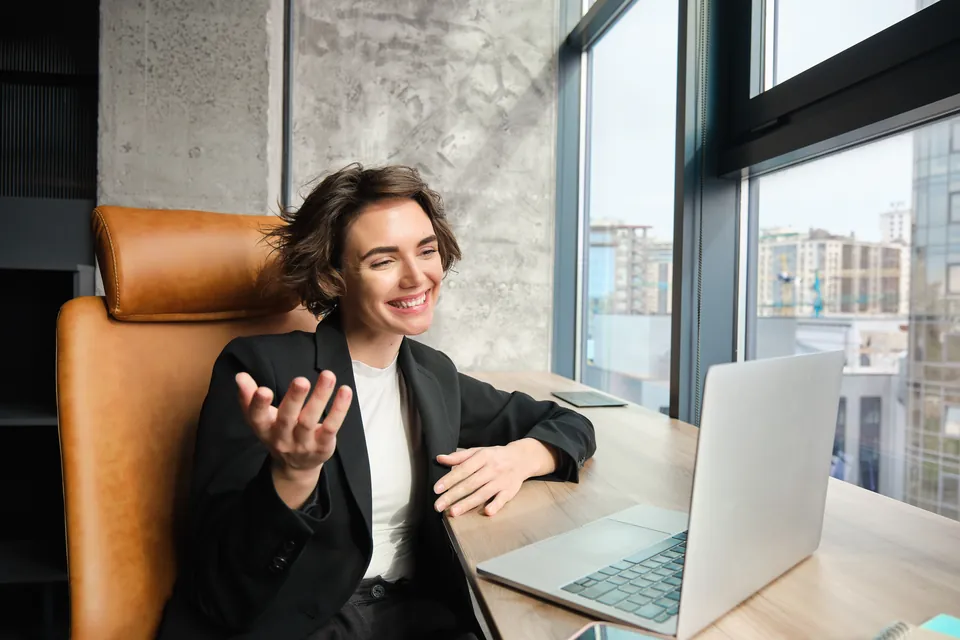 A person discussing work on a laptop call in an office